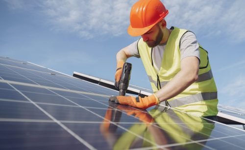 Male worker with solar batteries. Man in a protective helmet. Installing stand-alone solar panel system.