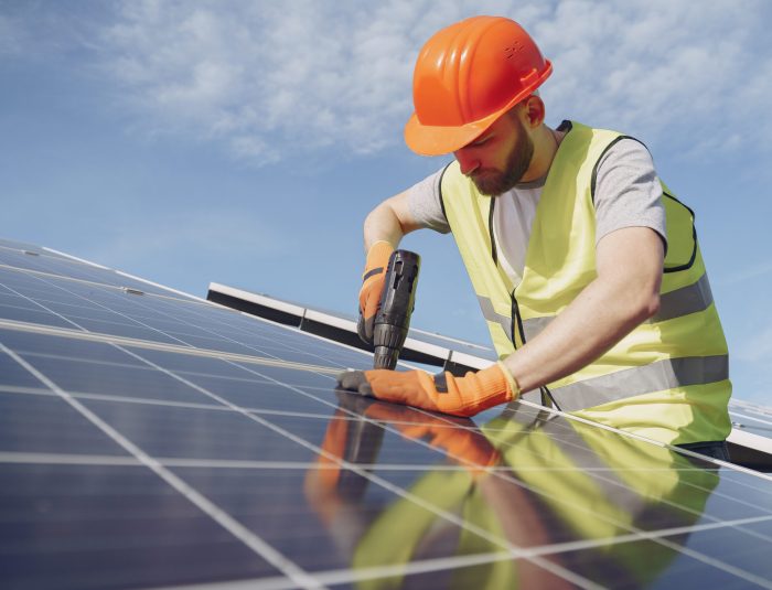 Alternative energy ecological concept. Male worker with solar batteries. Man in a protective helmet. Installing stand-alone solar panel system.