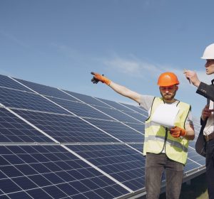 Businessman and worker near solar energy batteries. Business client showing photovoltaic detail to foreman. Two men making deal.