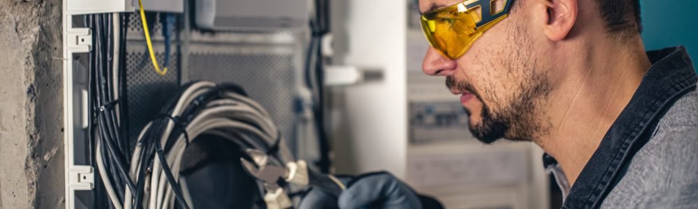 Man, an electrical technician working in a switchboard with fuses. Installation and connection of electrical equipment.