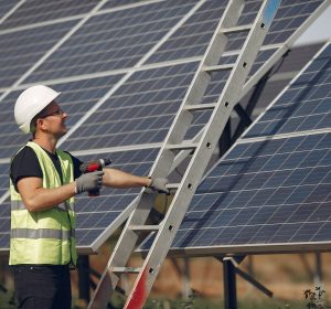 Engineer in a white helmet. Man near solar panel. Worker with a ladder